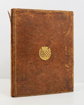 un vieux livre brun portant un emblème doré