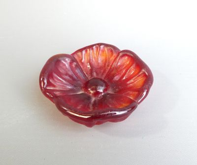 un objet en forme de fleur rouge sur une surface blanche