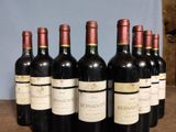 six bottles of red wine are lined up on a wooden table
