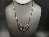 silver beaded necklace on a mannequin with a black background