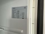 a white refrigerator with the door open and a sign on the door