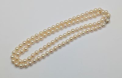 a close up of a pearl necklace on a white surface