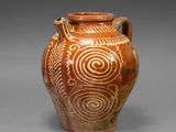 a brown vase with a design on it on a gray surface