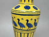 a yellow vase with blue and white designs on it