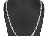 un collier de perles autour du cou d'un mannequin, muni d'un fermoir en or