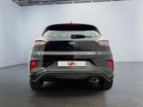 the rear end of a grey car in a white room