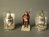 three figurines of a roman soldier in glass containers