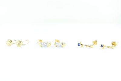 trois paires de boucles d'oreilles à clous en or et pierres bleues sur un fond blanc