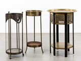 trois tables d'appoint en métal et en bois posées sur un sol en béton