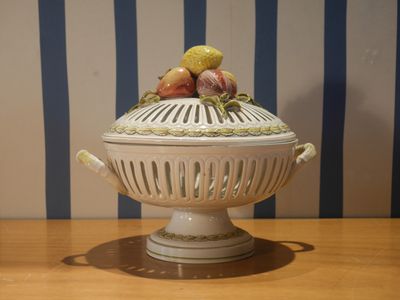 un bol blanc sur lequel sont disposés des fruits, posé sur une table en bois
