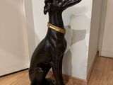 statue of a dog sitting on a base in the middle of a room