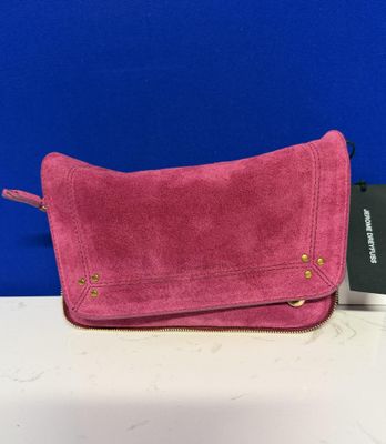 Le sac à main en daim rose se trouve à côté d'un passeport et d'un étui à passeport