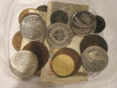 de nombreuses pièces de monnaie dans un récipient en plastique posé sur une table