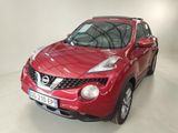 the red nissan juke suv is parked in a white room