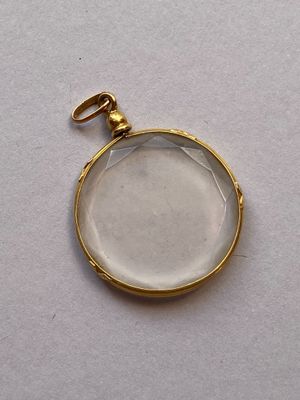une photo en gros plan d'un pendentif plaqué or orné d'un verre transparent
