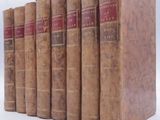 several old books are lined up in a row on a white surface