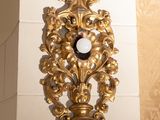 a gold clock on the wall of a bathroom
