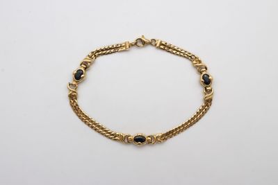 un bracelet en or orné de pierres noires sur fond blanc