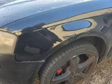 a black car that has been painted black and has a reflection of a person on the side of the car