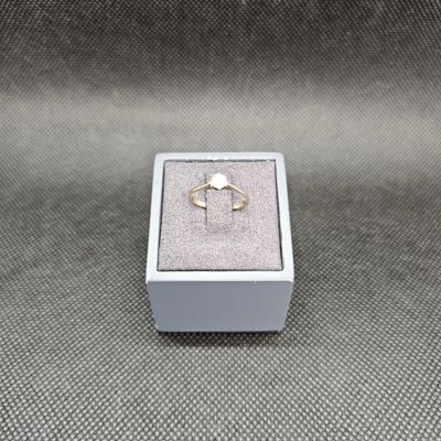 un gros plan d'une bague dans une boîte blanche posée sur une surface grise