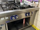 une plaque de cuisson en acier inoxydable dans une cuisine, sur laquelle sont posées des casseroles et des poêles
