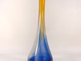 a blue and yellow vase sitting on a white surface