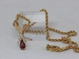 a close up of a necklace with a red stone on it