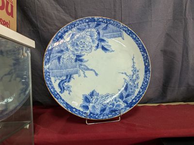 une assiette bleue et blanche posée sur une table à côté d'une horloge