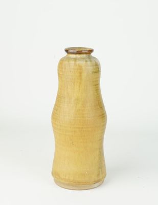 a yellow vase that is sitting on a white surface
