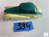 une petite voiture jouet verte et jaune sur laquelle est accrochée une étiquette de prix
