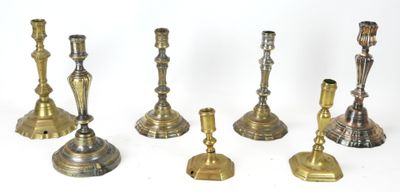 several brass candlesticks are lined up on a white surface