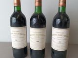 three bottles of red wine are lined up on a table