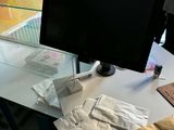 a desk with a computer monitor and many bags on it