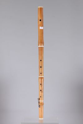 a wooden flute on a clear stand against a gray background