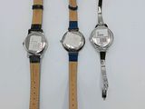 three watches are sitting on a white surface next to each other