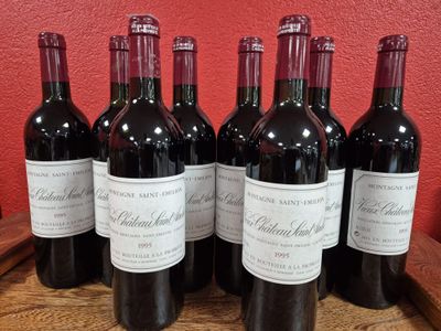 six bottles of red wine are lined up on a wooden barrel