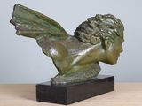 sculpture of a winged head on a wooden base on a table