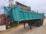 a green dump truck that is parked on a dirt road