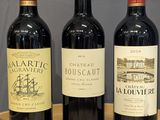 trois bouteilles de vin rouge sont alignées sur une table