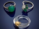 trois bagues et une bague ornée d'une pierre verte sur un fond bleu