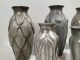three silver vases sitting next to each other on a white surface