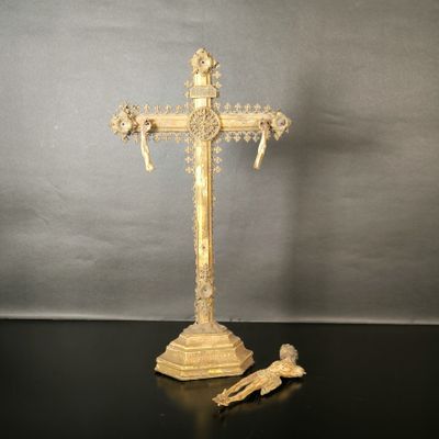 une croix ouvragée posée sur une table, à côté d'une paire de ciseaux