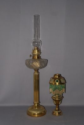 une lampe en or et un vase en verre posés sur une table