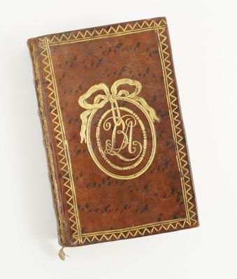 un vieux livre dont la couverture porte un monogramme plaqué or