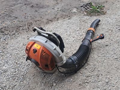 un petit ventilateur posé par terre à côté d'un tuyau d'arrosage