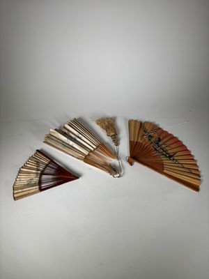 Plusieurs éventails en bois sont disposés sur une surface blanche