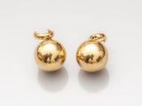 a pair of gold ball earrings on a white surface
