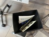 a black trash can with papers in it on the floor