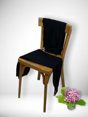 a wooden chair with a black seat and a vase of flowers