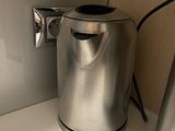a silver kettle sitting on a white counter next to a wall